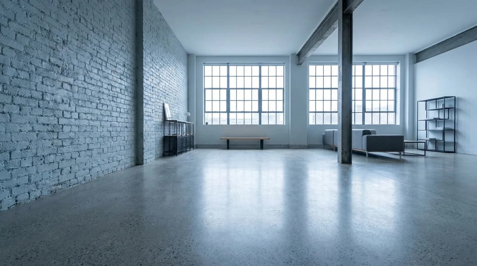 A polished concrete floor in an open plan Toronto loft, low winter sun from tall windows reflecting off the smooth grey surface